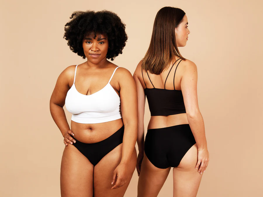 Two women wearing black and white lingerie against a beige background
