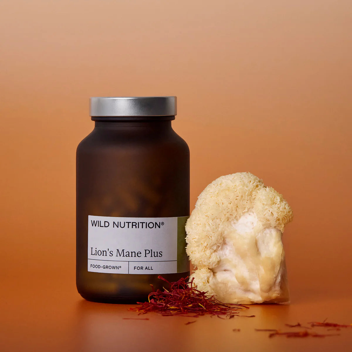Wild Nutrition Lion's Mane Plus supplement bottle with a piece of lion's mane mushroom on an orange background