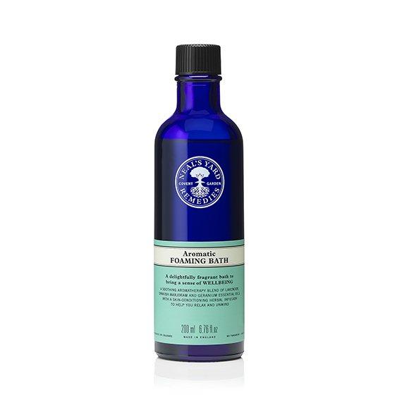 A blue bottle of aromatic foaming bath with a label displaying the product name and essential oils used.
